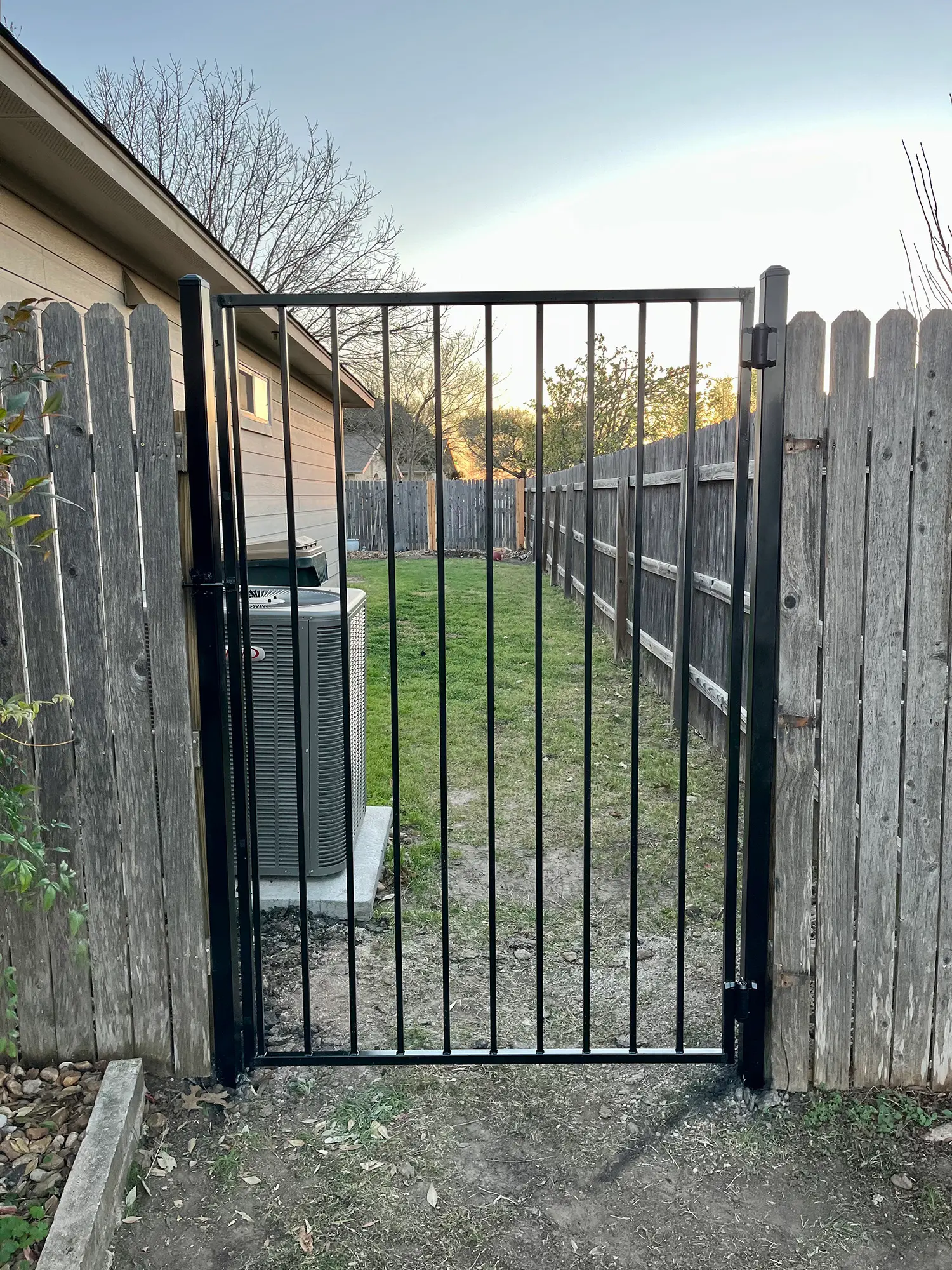 Black wrought iron gate set into a wood privacy fence in Austin, TX